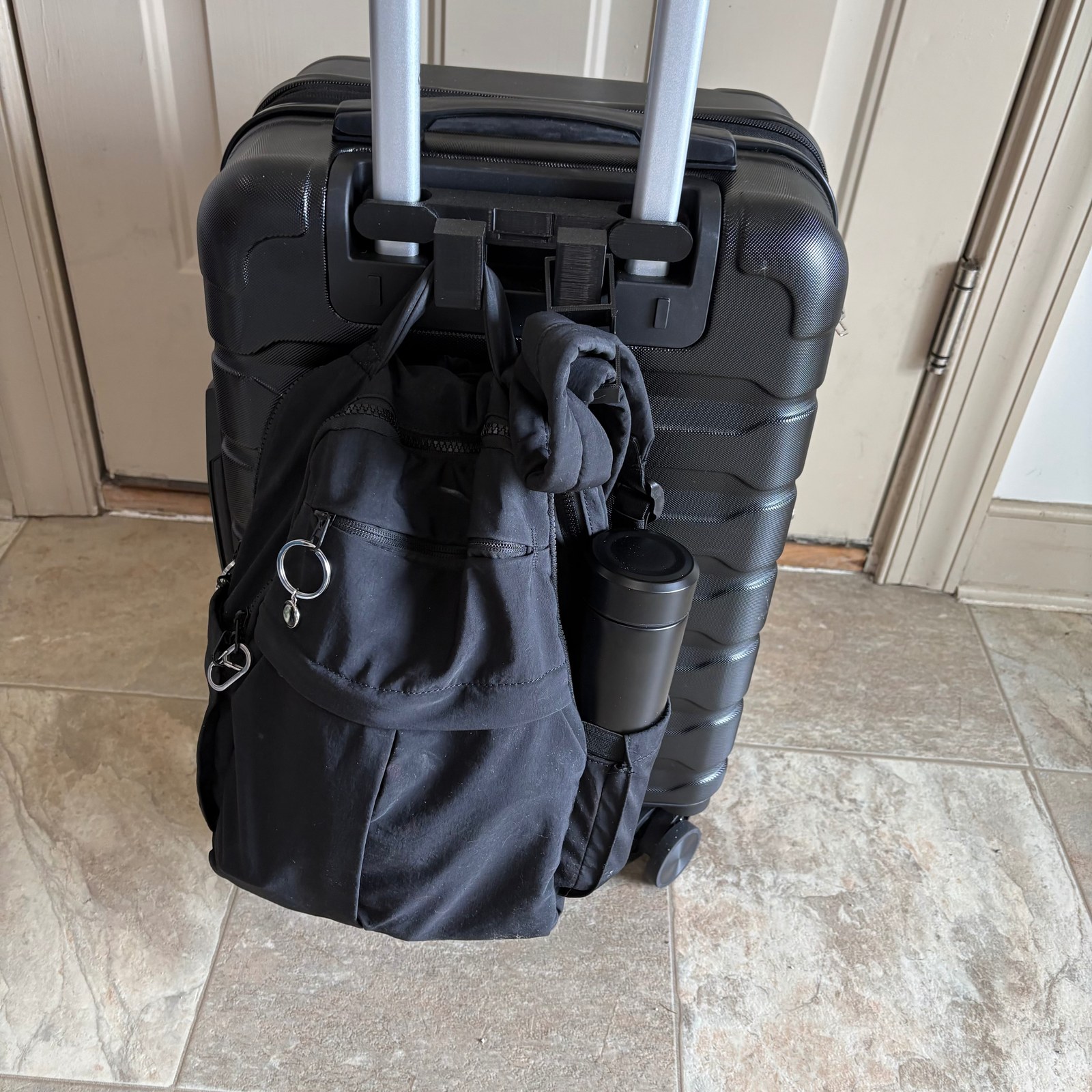 RAILTOTE hook holding a backpack, hoodie, and water bottle on a suitcase