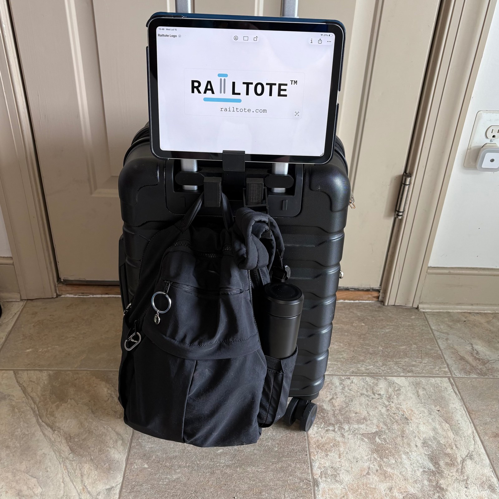 RAILTOTE Phone/Tablet Stand holding an iPad on a suitcase, backpack hanging below